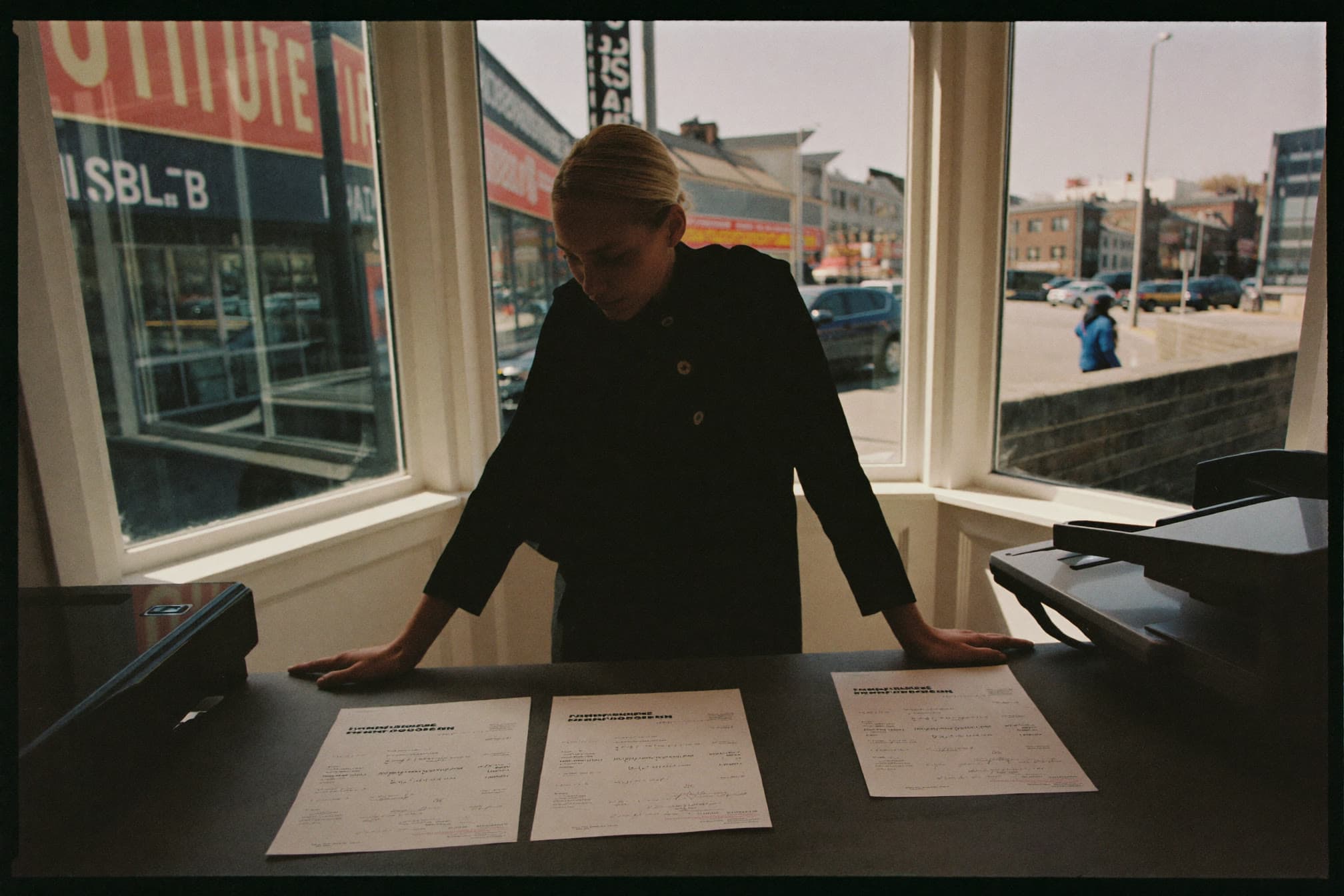Small business owner comparing two insurance documents at a storefront counter