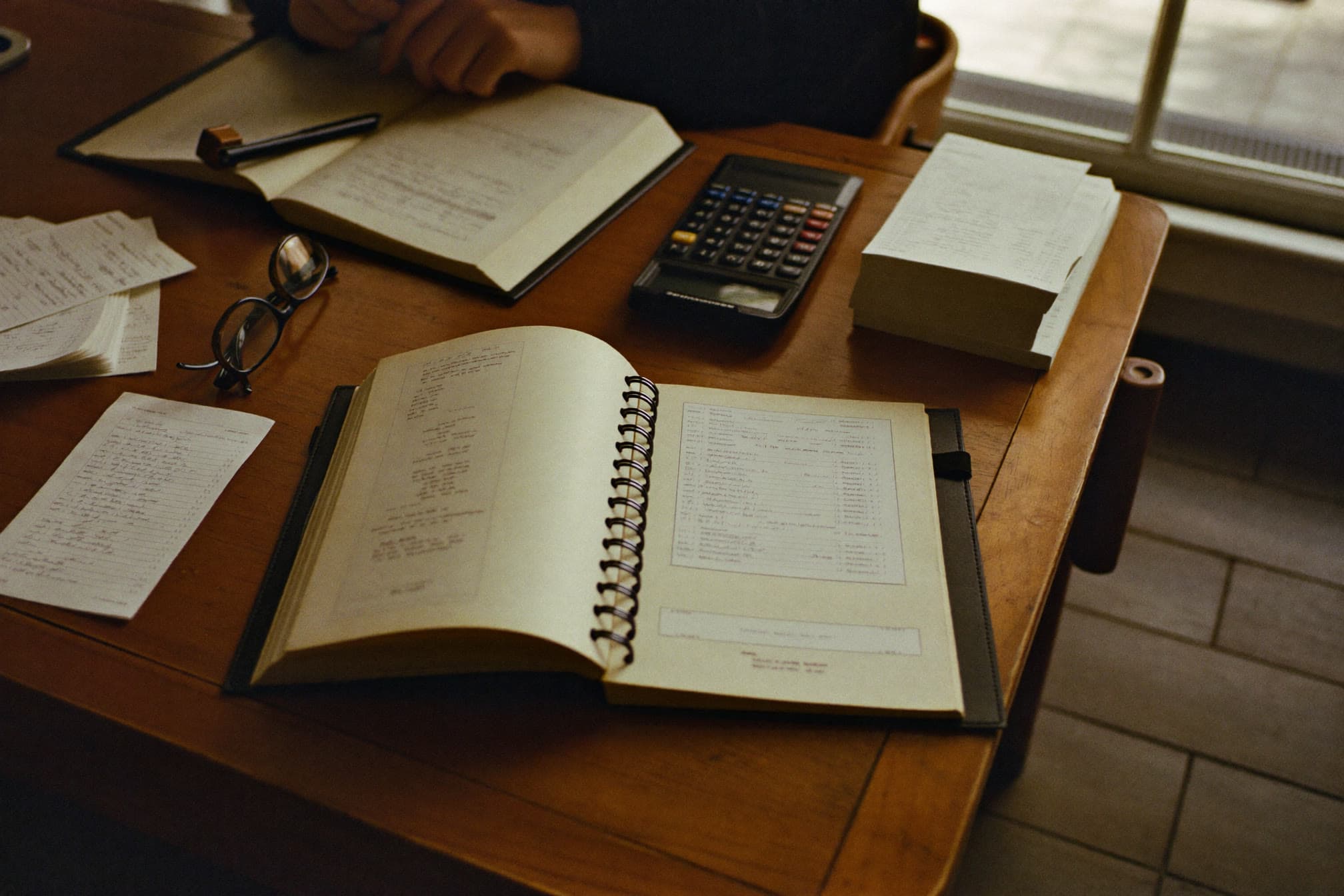 Desk with receipts, an open ledger, and a calculator for business tax records