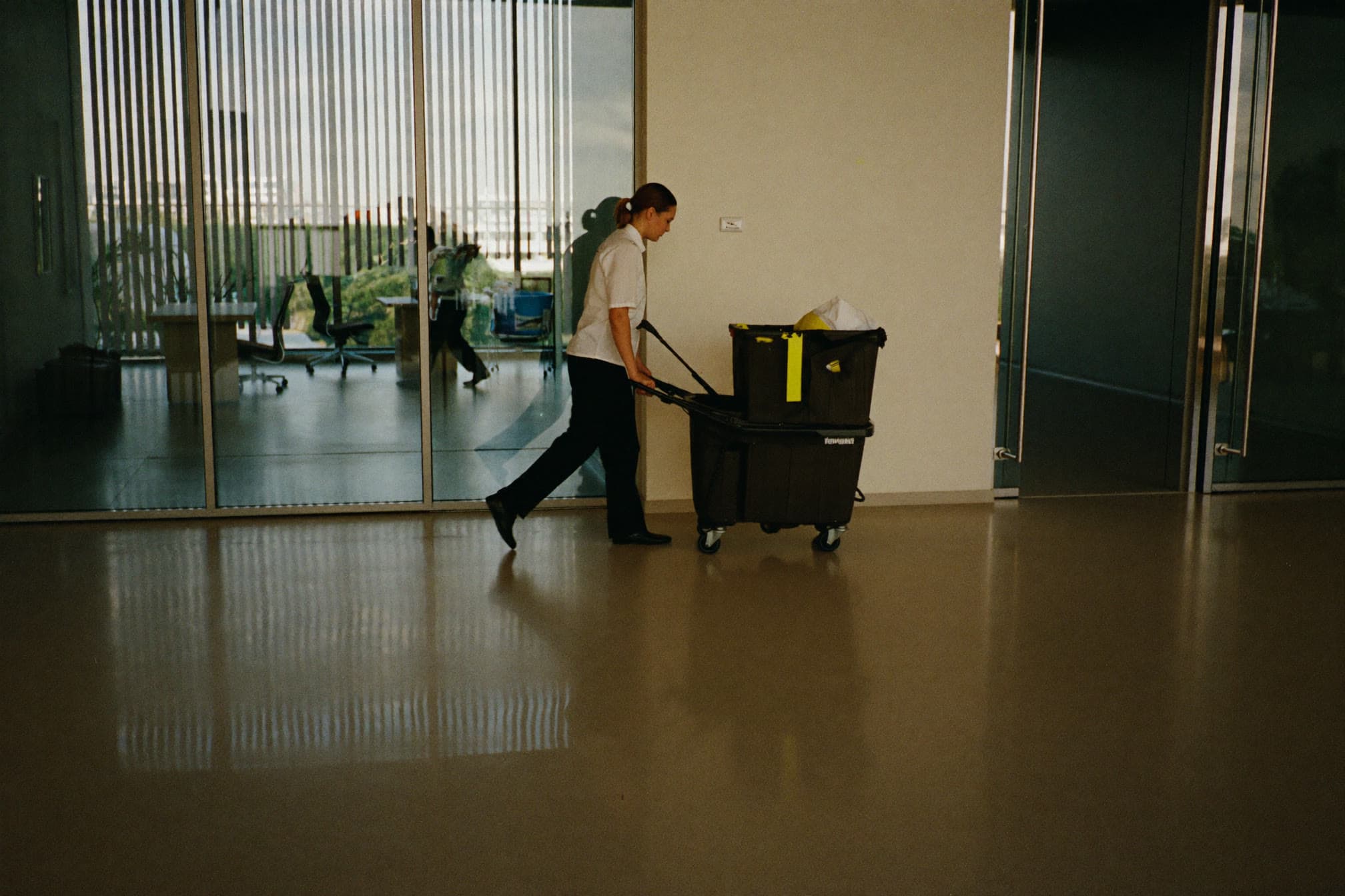 Commercial cleaner pushing a janitorial cart through a modern office lobby