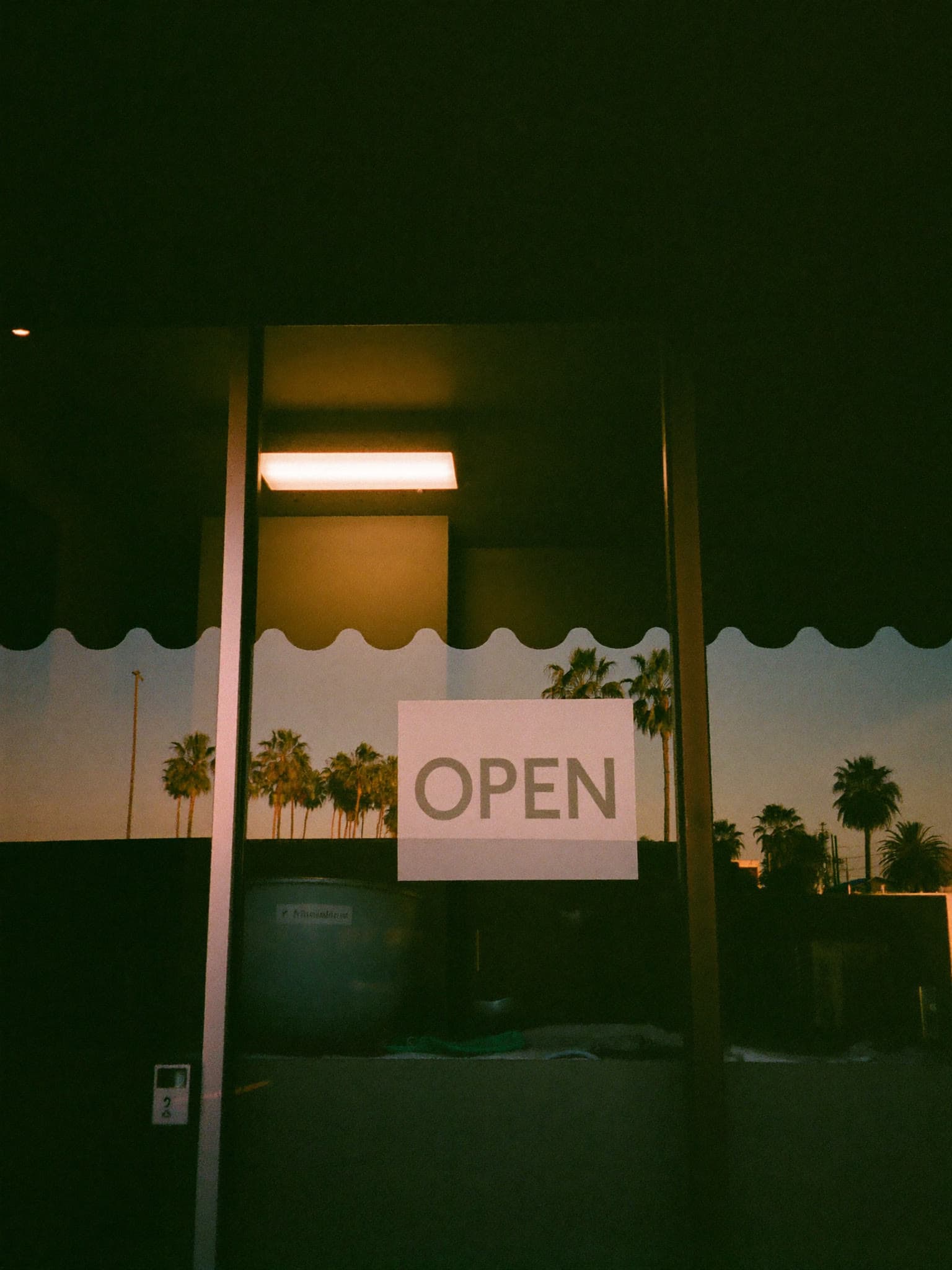 Small-business storefront window at dusk with an open sign